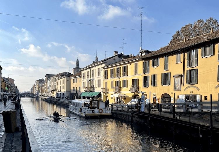 A photo of a tourist boat and a kayaker in the Naviglio Grande