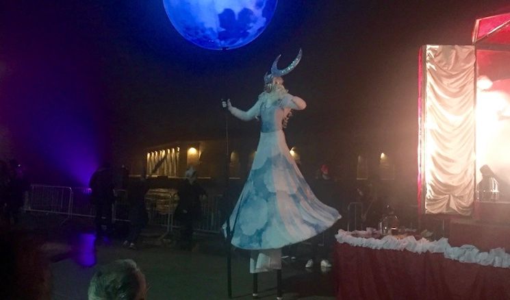 A Venice Carnevale performer on stilts, holding a moon.