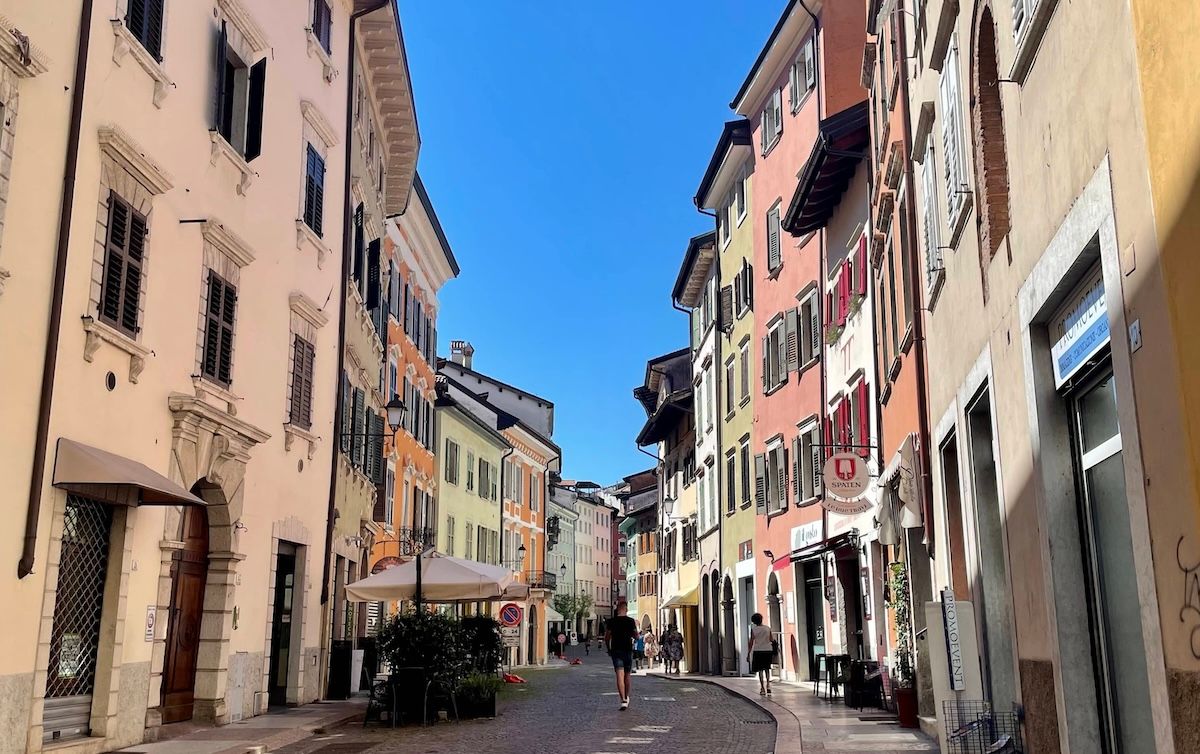 Walking the streets of Trento, Italy. Colorful buildings with Italian shutters line the perimeter.