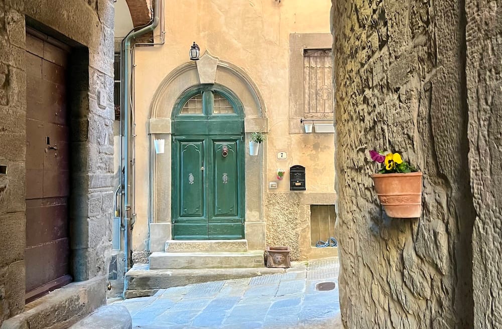 A colorful door in Cortona, Italy, complete with flower pots lining the street.