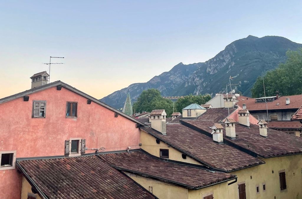 Italian roofs at sunset, with Trento's mountain ranges towering in the background.