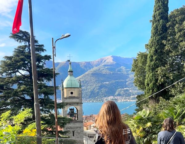 A brunette woman's hair shines in the sun looking out at Lake Como, Italy.